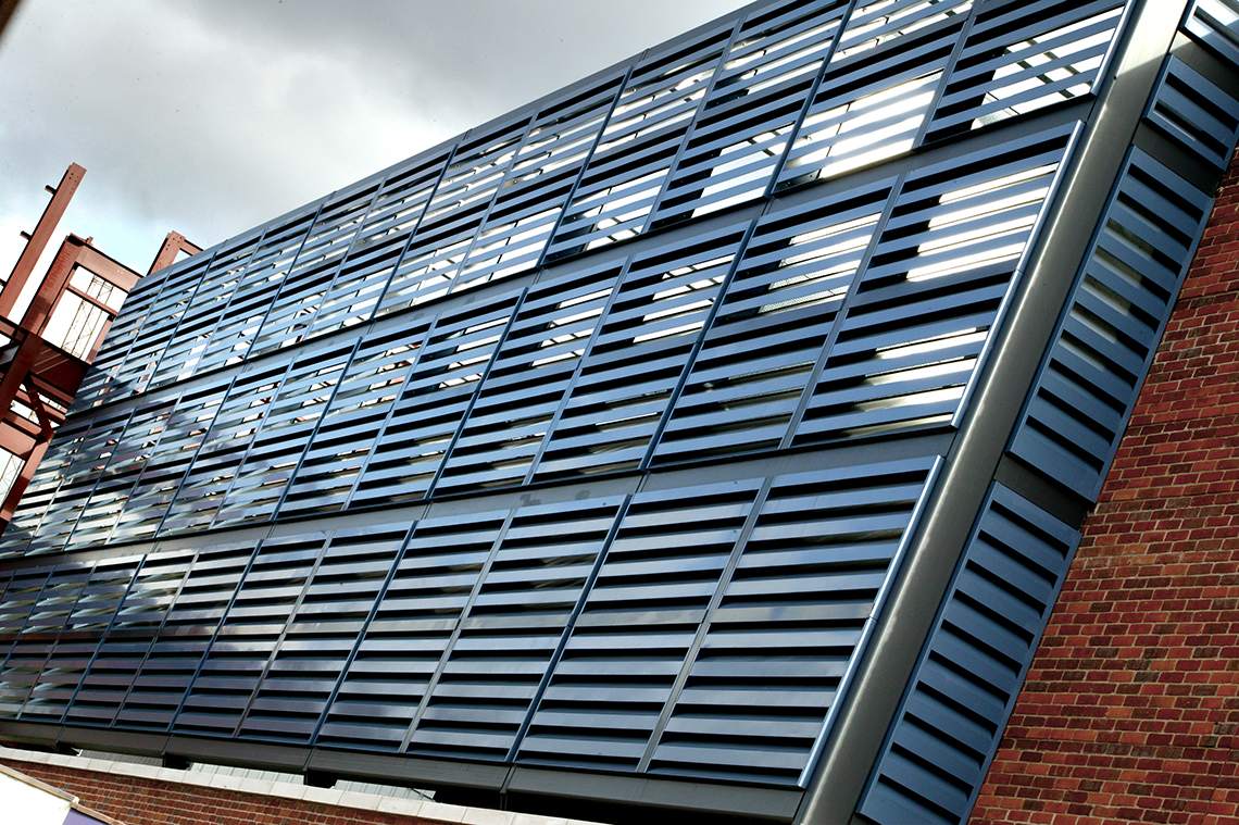 Akustisk fasadebekledning (akustiske Louvers Slimshield™) som demper støy montert på et parkeringshus.